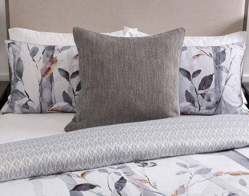 Front view of our Tamarak Euro Sham leaning against coordinating pillows on a half-dressed white bed.