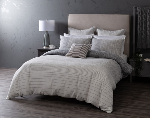 Angled view of our Halston Duvet Cover dressed over a queen bed in a plain grey bedroom.