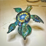 Blue and green colored sea turtle sculpture with blue and yellow flower