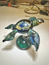 Blue and green colored sea turtle sculpture with blue and yellow flower