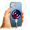 A hand holding a smartphone with a round, blue and white magnetic wireless charger attached to the back.