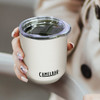A drink bottle featuring a cream-coloured vacuum tumbler with a clear lid and a logo.