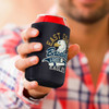 A drink bottle covered with a black stubby cooler, featuring a logo and held by a person in a checked shirt.