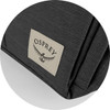 A close-up of a dark grey backpack fabric featuring an Osprey logo patch on the side.