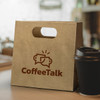 A medium, brown die-cut paper bag with a handle and a coffee cup beside it, featuring a logo.