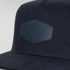 A navy flat peak cap featuring a textured patch and a logo on the front. The design is sleek and modern.