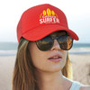 A red trucker cap with a logo, worn by a person with sunglasses and a beach backdrop.