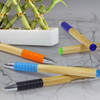 A set of Bamboo Twist Pens in various colours: orange, blue, green, and black, next to a bamboo arrangement.