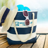 A blue and white striped tote bag with sunglasses, a hat, and flip-flops inside. It has a logo on the front.