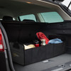 A black trunk organiser with various items, including a drink bottle, towels, and a bag, inside a car boot.