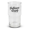 A clear stackable glass tumbler featuring a black logo. The glass has a cylindrical shape with a wider base.