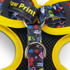A pet harness in black with vibrant yellow accents, featuring colourful patterns and metallic rings.