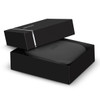 A black gift box partially open, revealing a sleek black headphone case inside. The box features a simple logo.