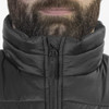 A black puffer vest with a high collar and zip front, worn by a person with a beard. The vest has a branded logo.