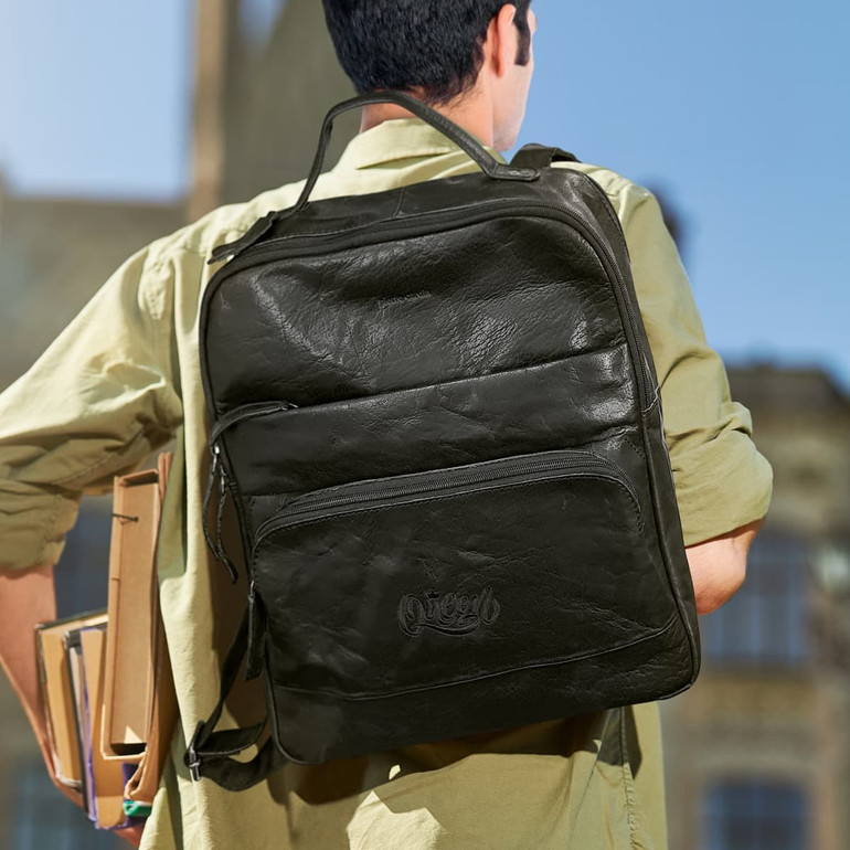 A black leather backpack with multiple compartments, being carried on the back of a person.