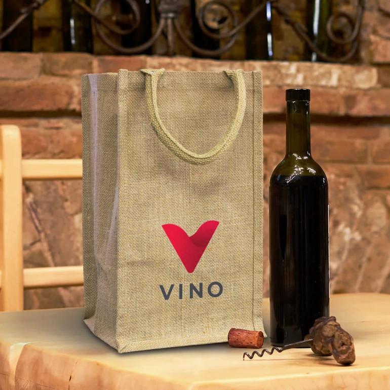 A jute wine carrier in natural colour with a red logo, alongside a dark wine bottle and cork on a rustic table.