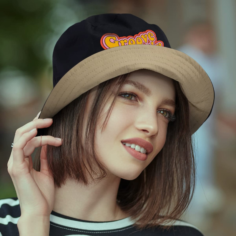 A reversible ripstop bucket hat featuring a black top and a tan brim, with a logo on the front.