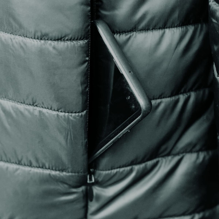 A puffer jacket with a zippered pocket, containing a smartphone, in a dark colour.
