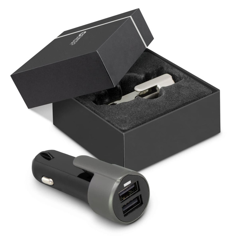 A black and grey USB car charger is displayed next to its box with a foam insert, featuring a logo.