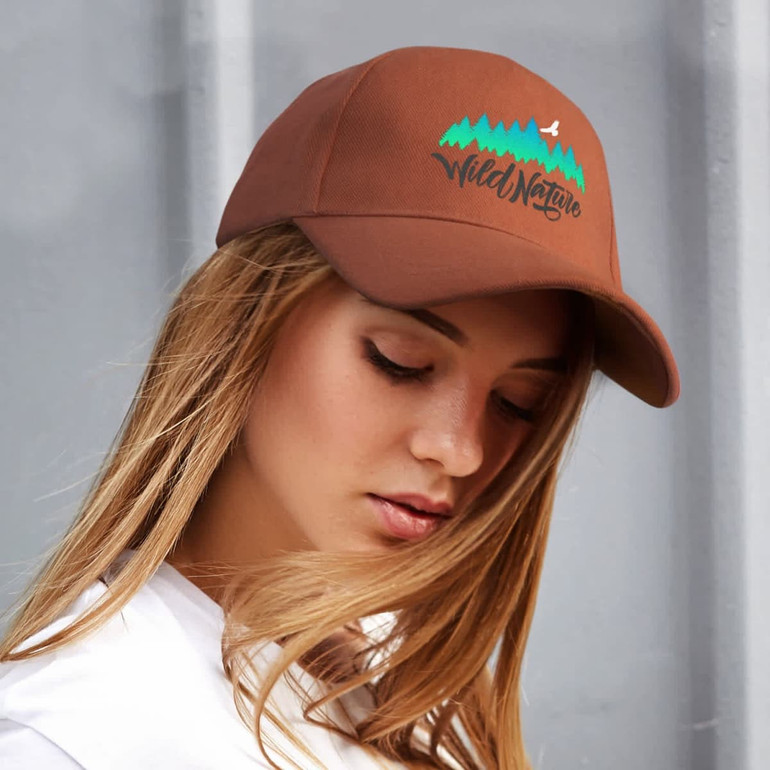 A brown cap with a logo, featuring a colourful mountain design. The cap is worn by a person with long hair.