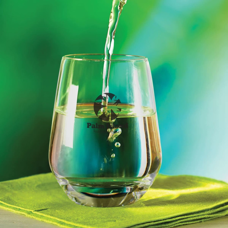 A stemless glass filled with liquid, featuring a reflective surface and a colorful background.