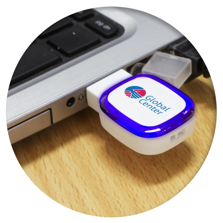 A white and blue Zodiac 4GB flash drive plugged into a laptop USB port, featuring a logo.