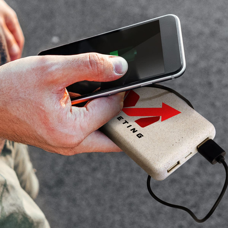 A power bank in a light colour with a logo, being used to charge a smartphone.