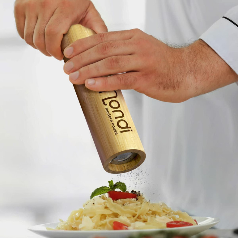 A bamboo pepper mill in a recyclable cardboard packaging, featuring a minimalist design and a logo.