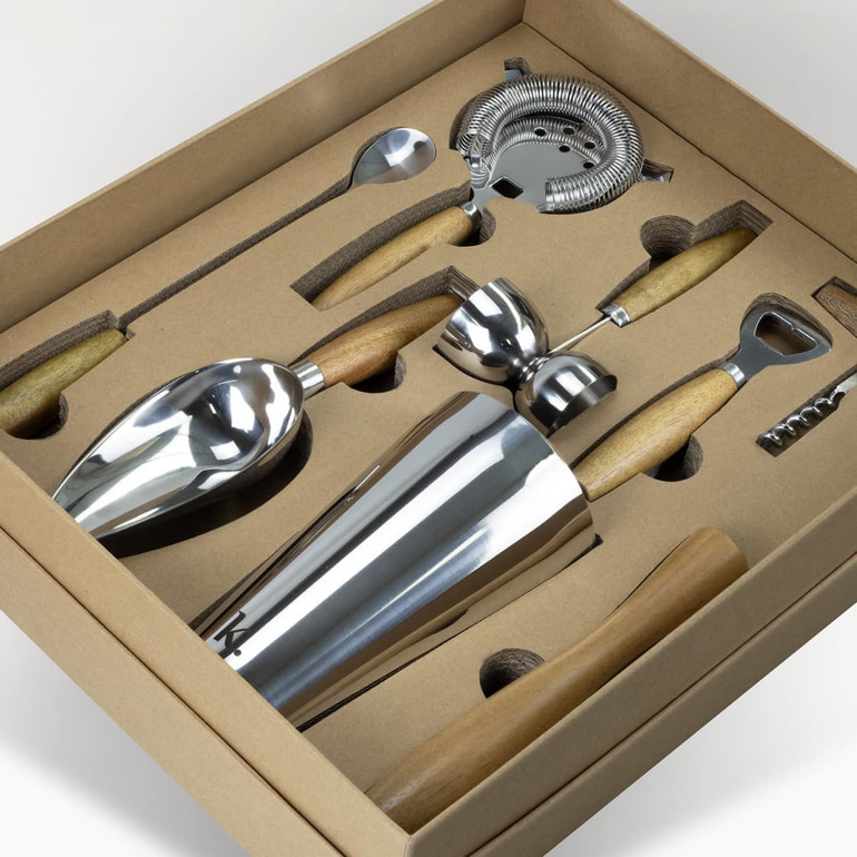A cocktail set featuring stainless steel tools with wooden handles, neatly arranged in a brown box.