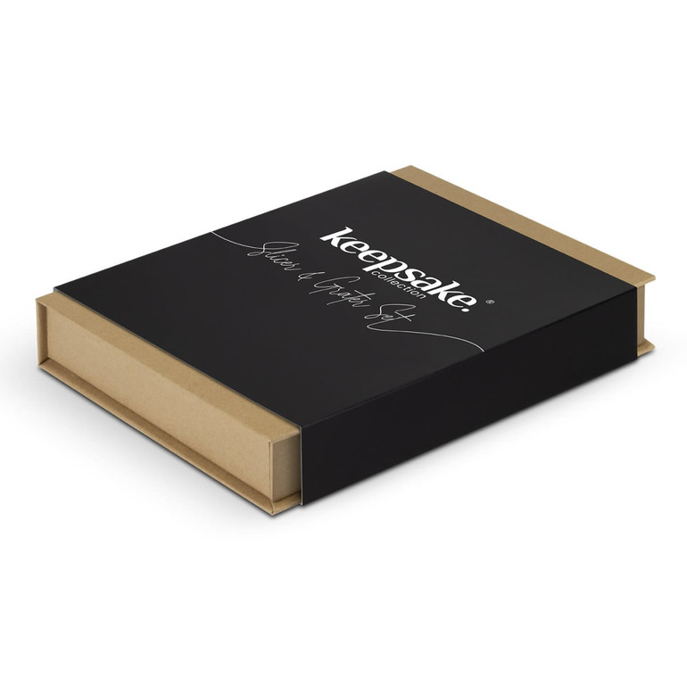 A black box with a gold base, featuring the Keepsake logo, containing kitchen slicer and grater utensils.