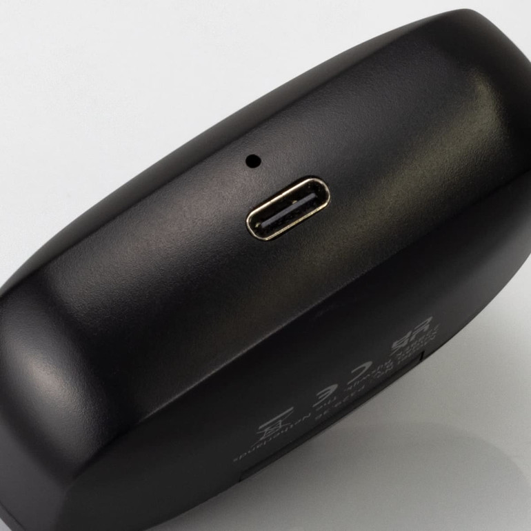 A black charging case with a USB-C port, used for wireless earbuds. The case has a sleek design and minimal branding.