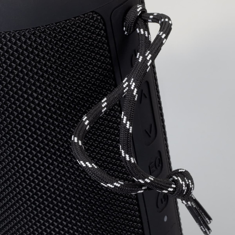 A black Bluetooth speaker with textured surface and a decorative cord attached.