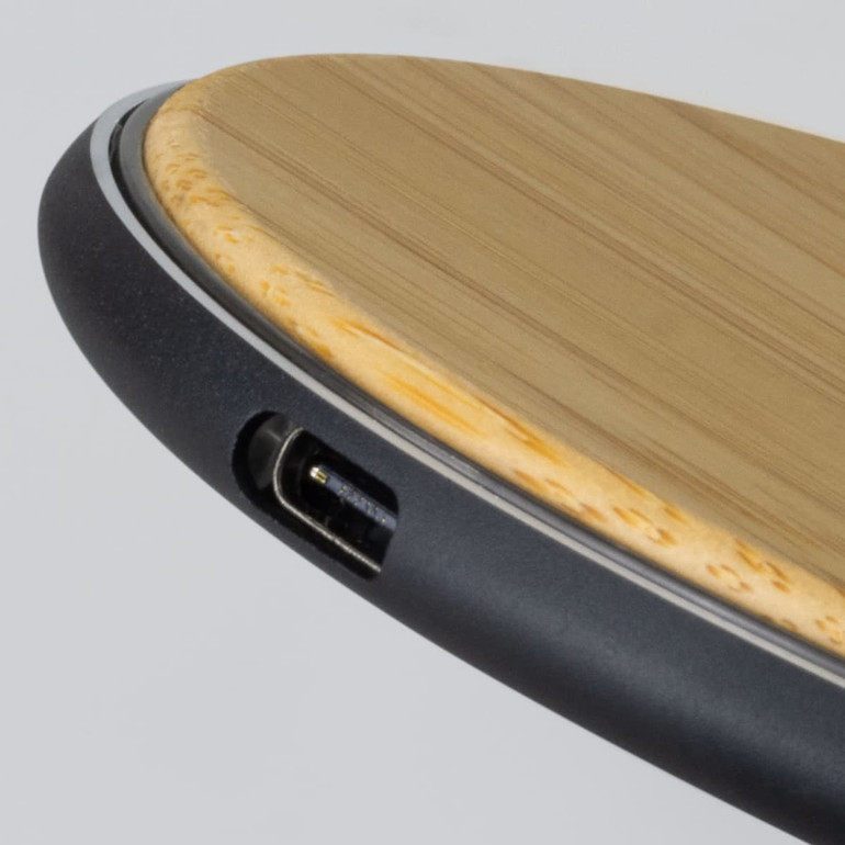 A bamboo wireless fast charger featuring a sleek black edge and a USB port.