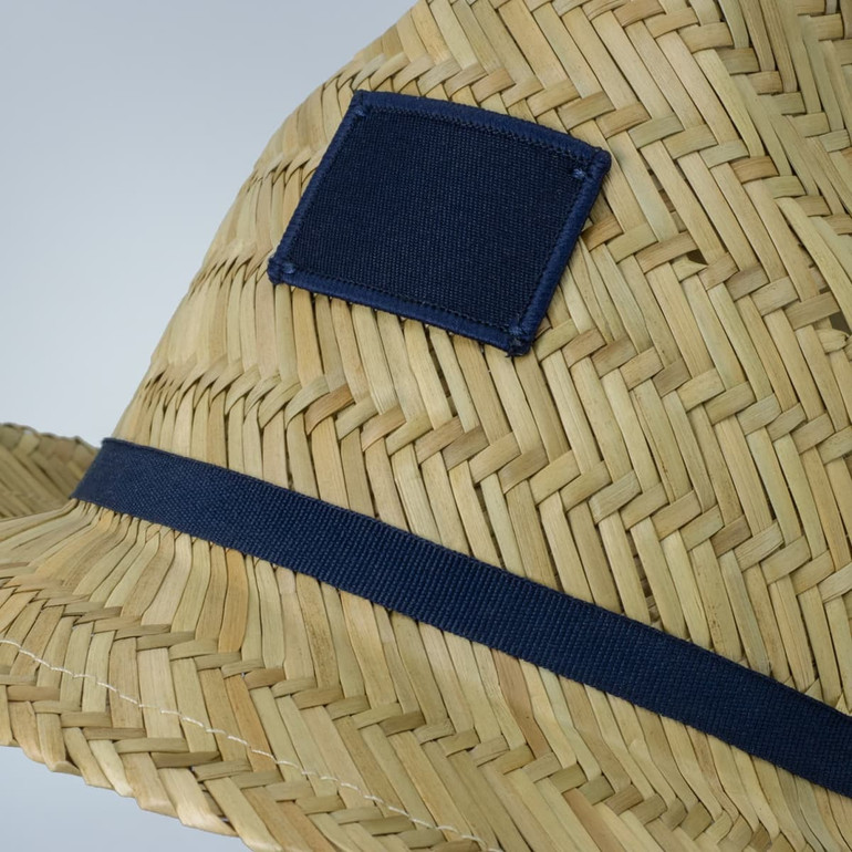 A straw fedora hat featuring a navy band and a square patch. The design showcases woven straw patterns.