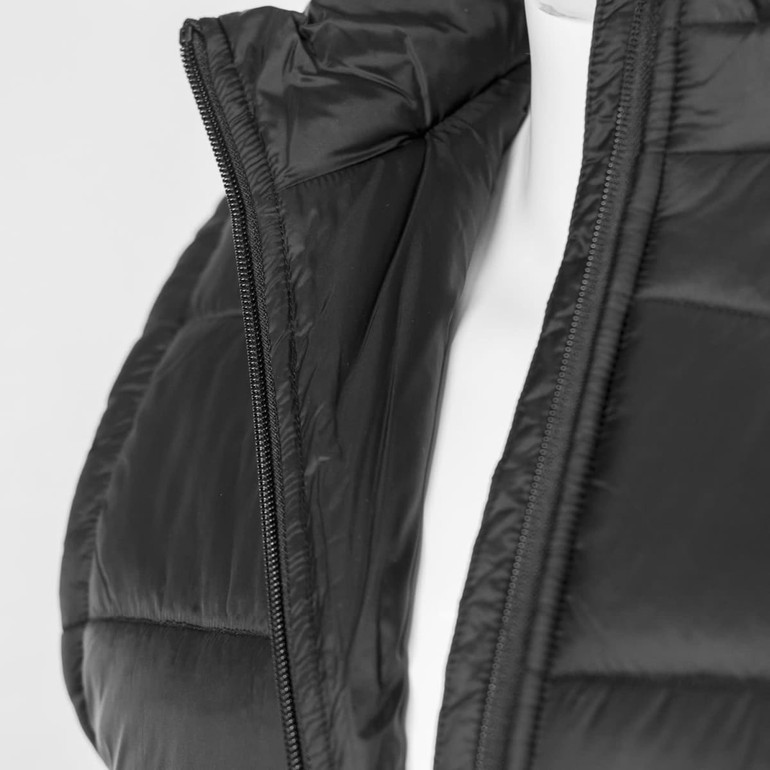 A black puffer vest with a zippered front, featuring a high collar and smooth fabric texture. It has a logo.
