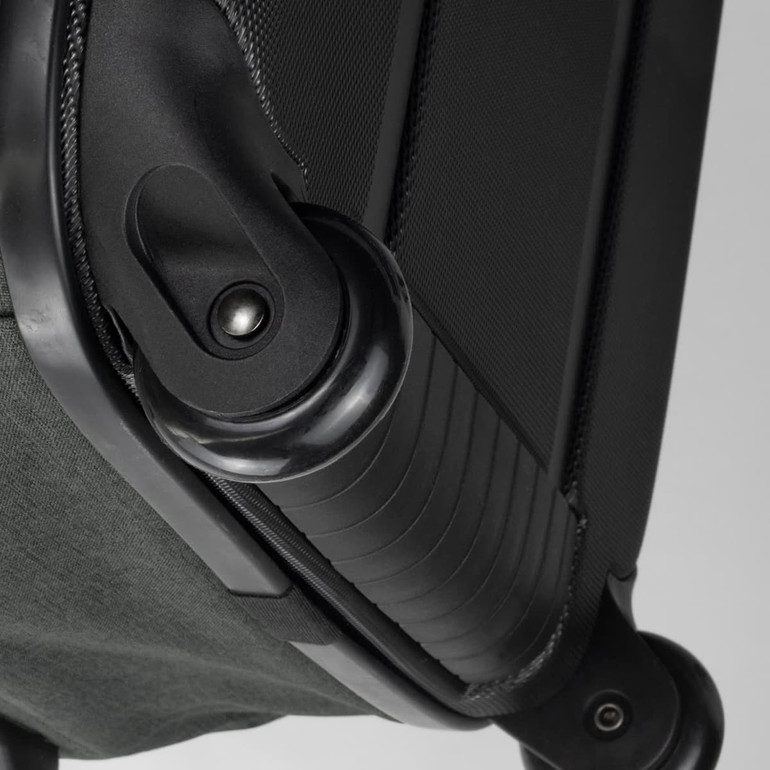 A close-up of the wheel mechanism and handle of a small black and green Rollink Flex Earth suitcase.