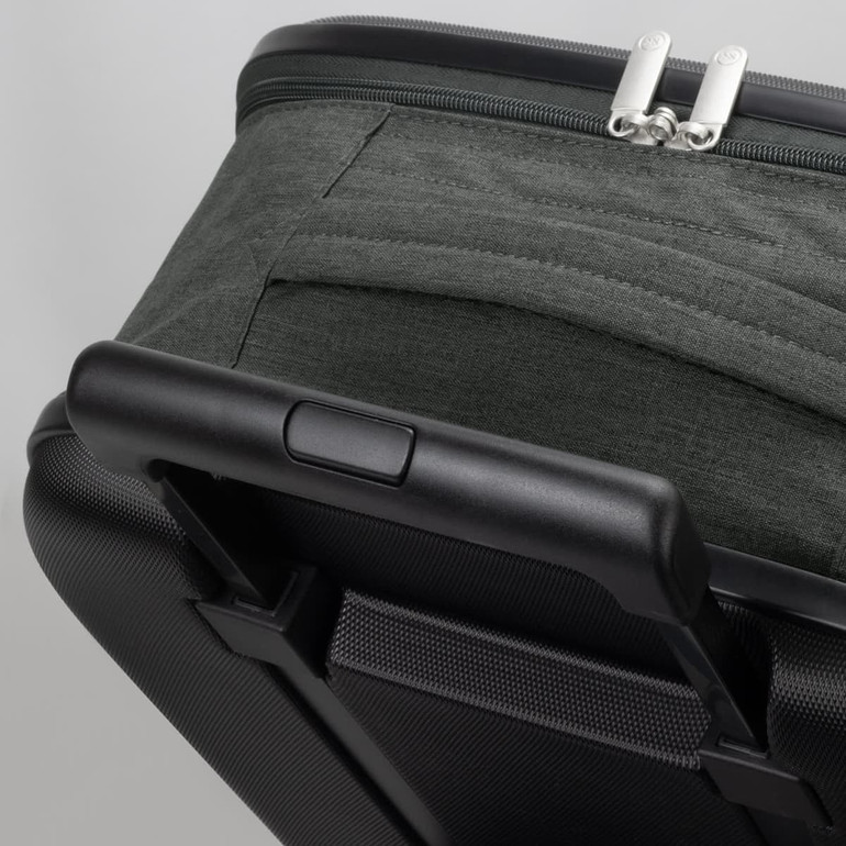 A small wheeled suitcase in dark green fabric with a black hard shell and a retractable handle.