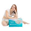 Model wearing BeDry Premium, sitting and leaning forward on a bag of BeDry Premium adult diapers.