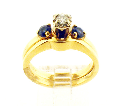 This is a 14 karat yellow gold engagement ring set with a diamond center stone and blue sapphire side stones. The total weight of both rings is 5.7 grams and is for a ring size of 6.
