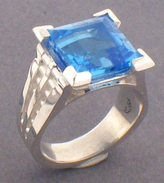 This is a sterling silver and princess cut London blue topaz ring with decorative sides.  The London Blue Topaz is 10 x 10mm in size.  The ring weighs 11.0 grams and is a ring size 6.5