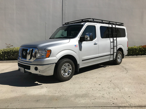 A silver-colored Nissan NV van with a black powder coated Weekender Roof Rack from Aluminess Products.