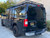 A gloss black Nissan NV van with a side ladder, surf pole, and surf hooks from Aluminess Products.