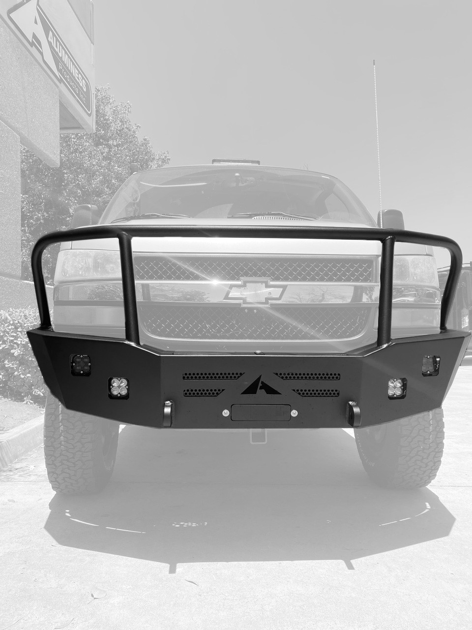 A parked silver truck in a parking lot with an Aluminess Front Bumper - Express 2003+.