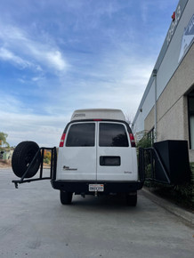 Rear view of a white Express van featuring Aluminess Rear Bumper with swing arms open parked on the street.