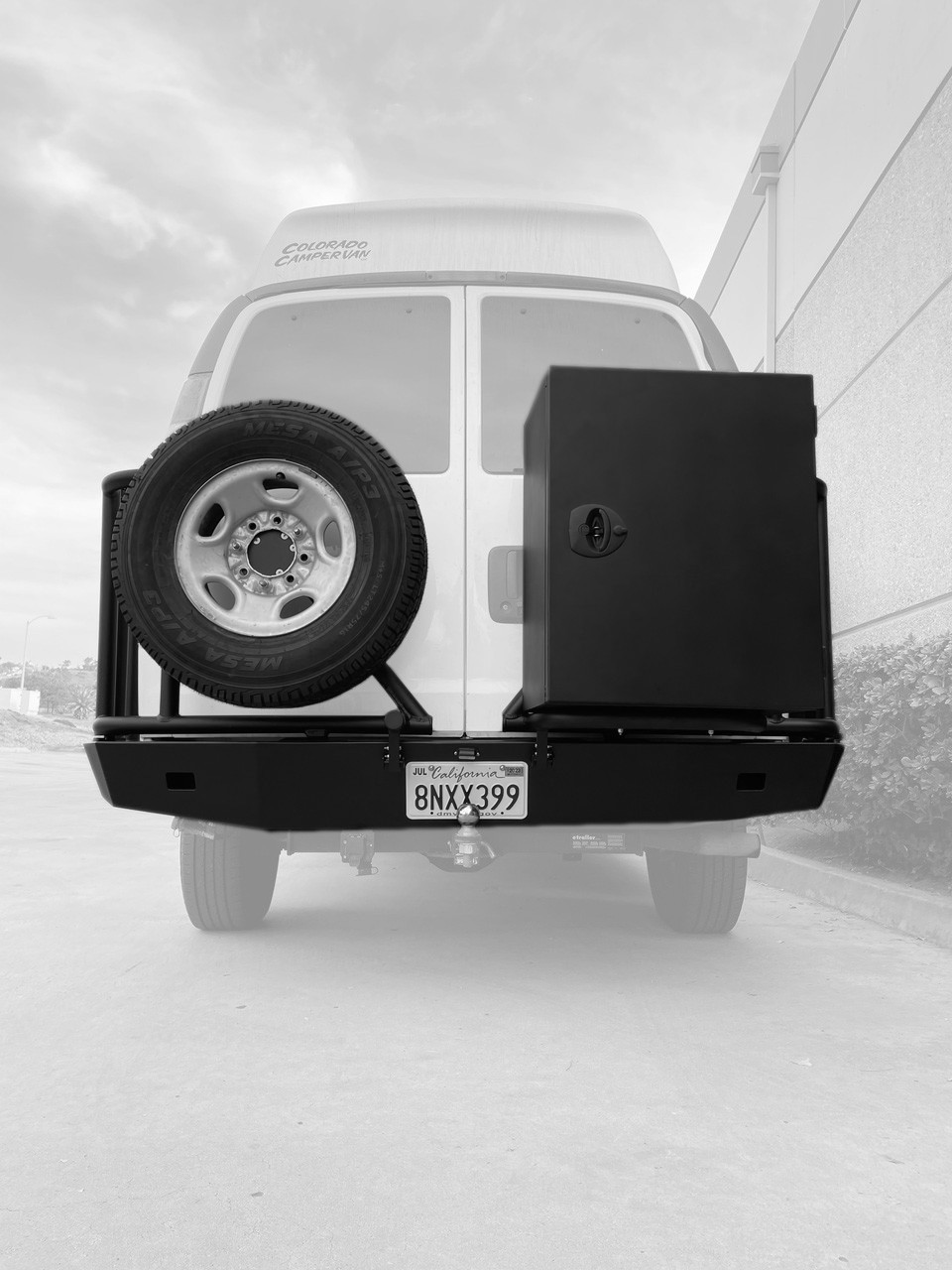 Rear view of a white Express van featuring Aluminess Rear Bumper parked on the street.