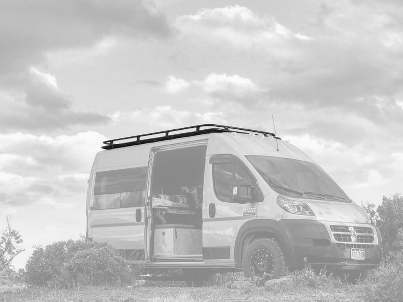 White Dodge RAM Promaster van highlighting Aluminess Weekender Roof Rack in the desert.