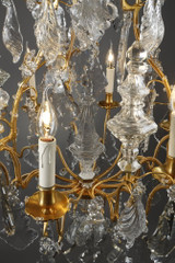 Una lámpara de araña de seis luces en bronce dorado, adornada con colgantes y dagas de cristal tallado