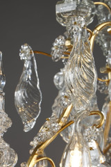 Una lámpara de araña de seis luces en bronce dorado, adornada con colgantes y dagas de cristal tallado
