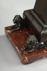 Pendule à lobélisque, style Charles X, socle en marbre rouge avec lions antiques.