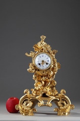 ROCAILLE STYLE CLOCK IN GILDED BRONZE, DECORATED WITH A PUTTO IN A SHELL